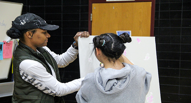  Young girl painting with adult woman